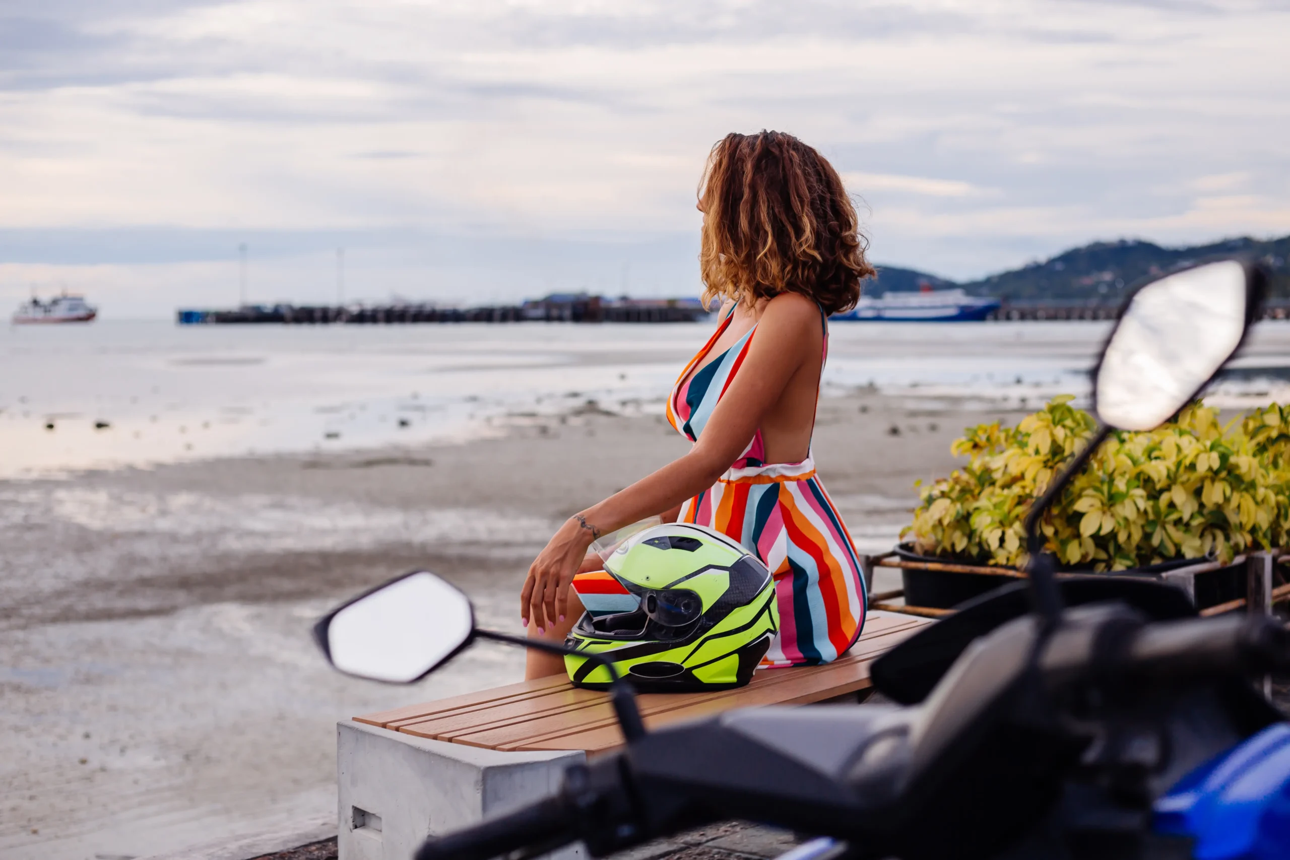 feliz-mujer-caucasica-del-motorista-en-colorido-vestido-de-verano-de-vacaciones-con-casco-de-moto